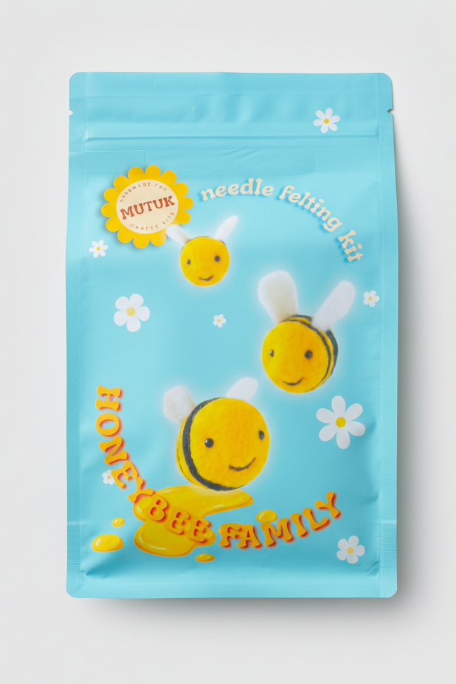Packaging of a needle felting kit with bee-themed design on a marble surface.