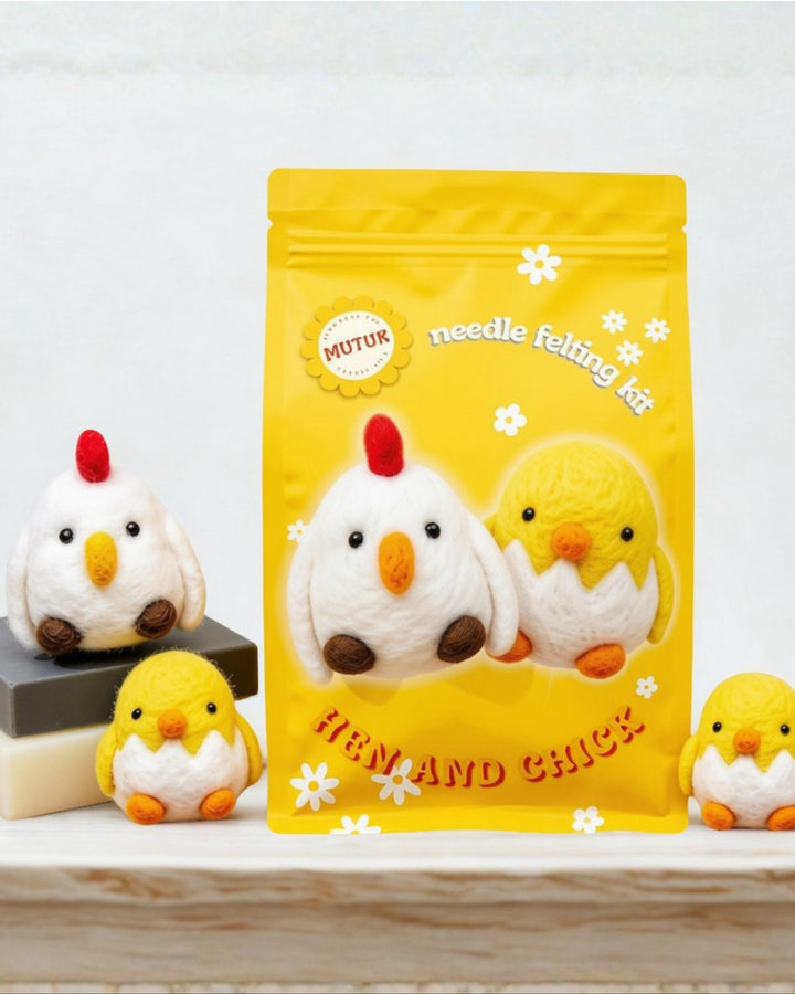 A yellow 'Mutuk' needle felting kit pouch featuring hen and chick designs, displayed on a light wooden surface with three felt hen and chick figures arranged around it.